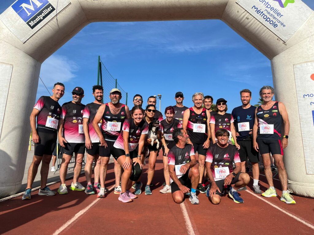 groupe de coureurs du club Perols Footing sous une arche de départ sur une piste de course à pieds