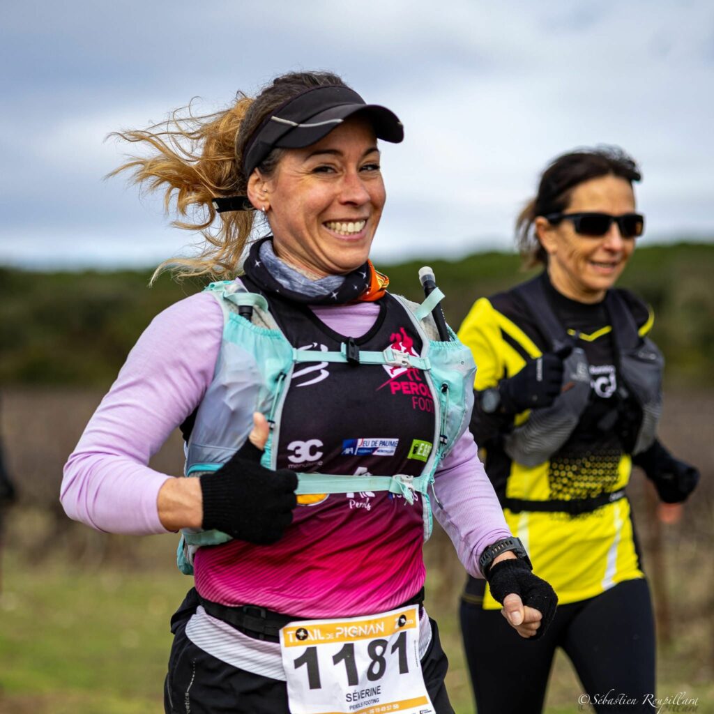 femme qui sourit en courant lors d'une compétition de course à pieds